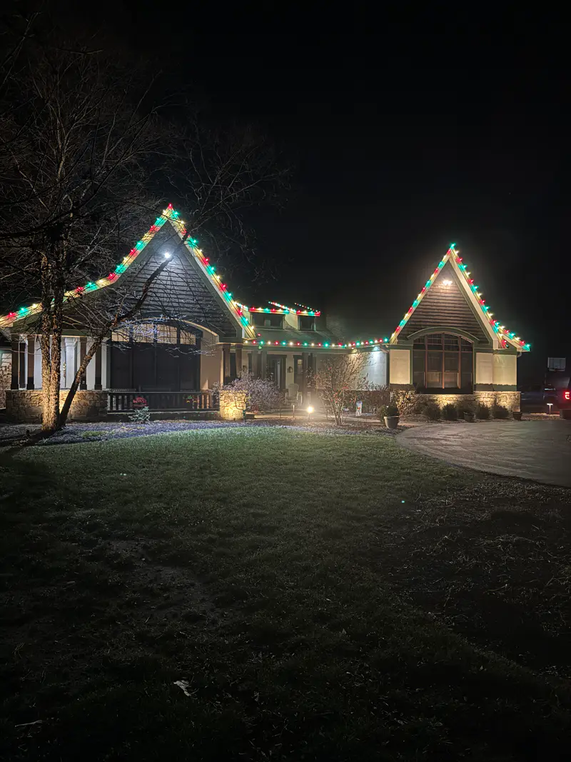 Craftsman at night with red, green and white bulbs running over two peaks and the garage