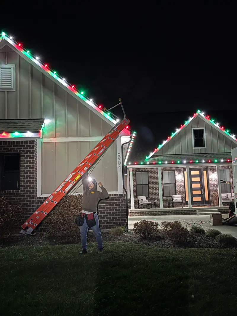 Two lit gables at night with a ladder still leaning on the nearer one