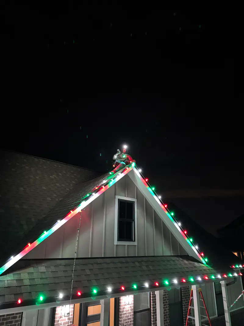 A gable peak at night lined with evenly spaced red, green and white bulbs