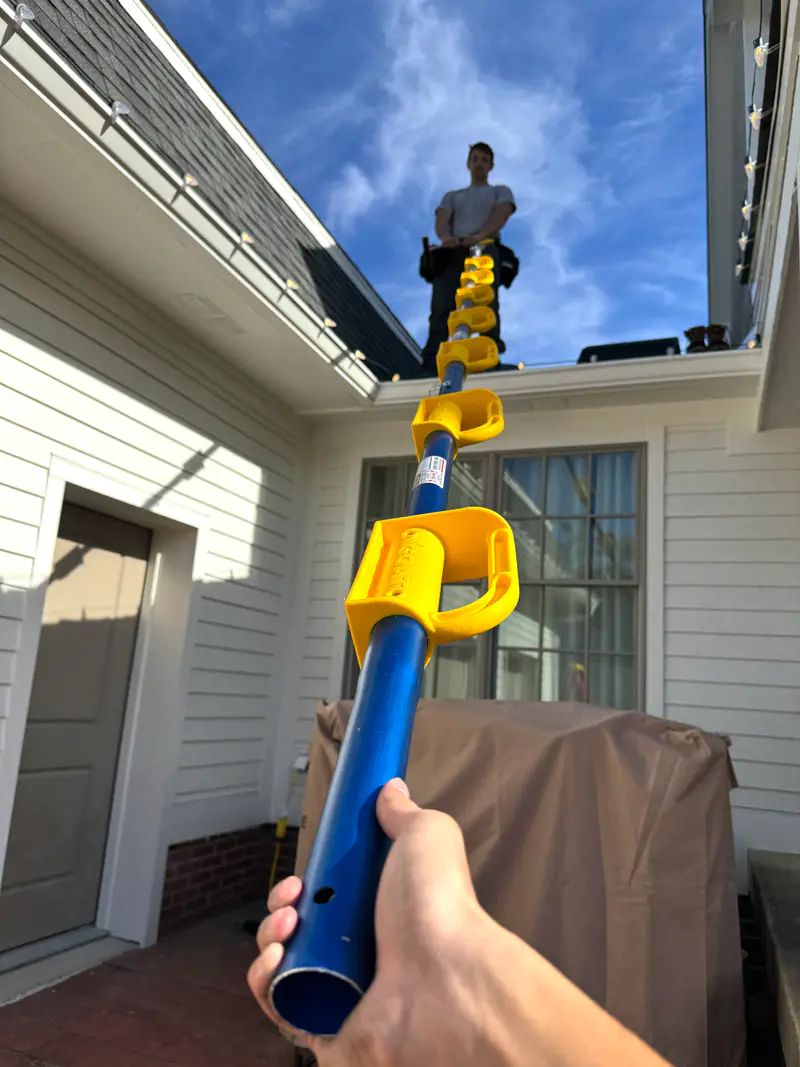A clip pole raised to the gutter while an installer works the roof above