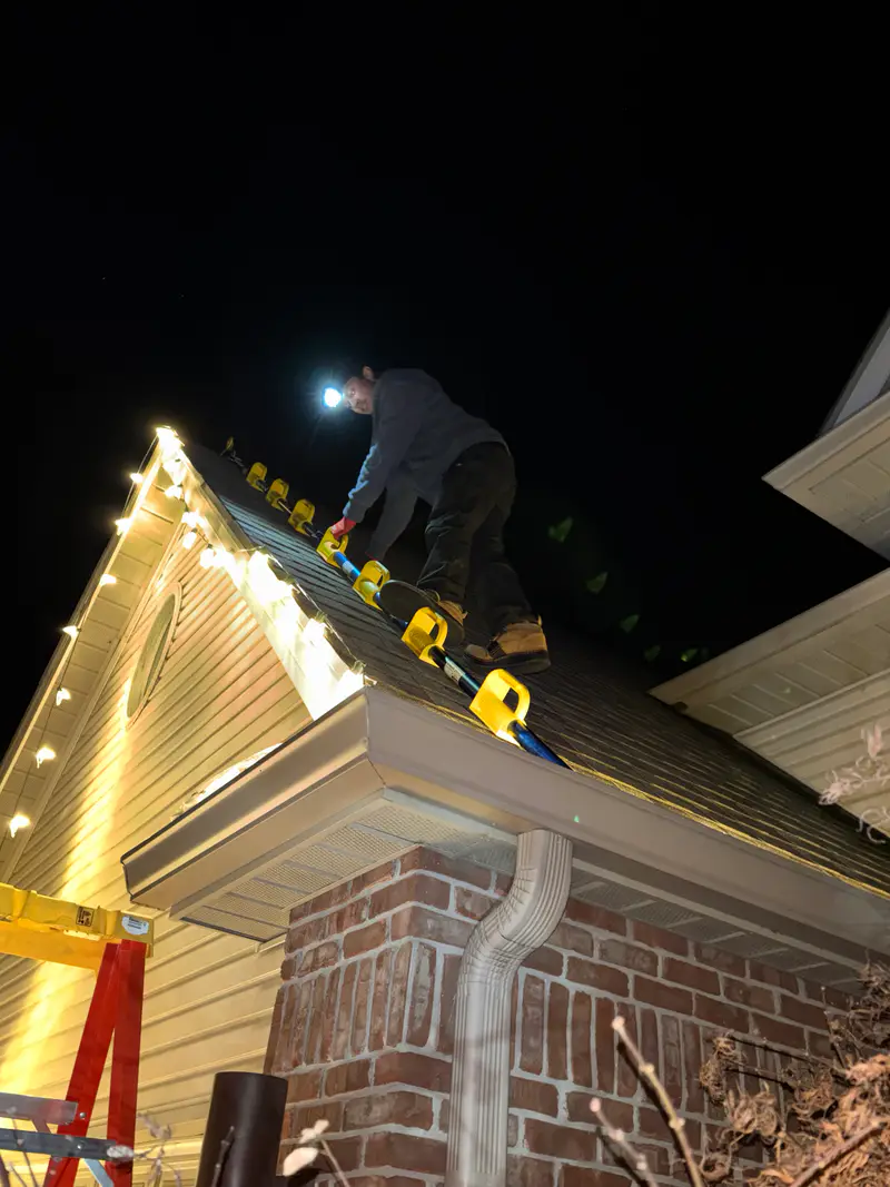 Working on a roof at night by headlamp beside a freshly lit gable