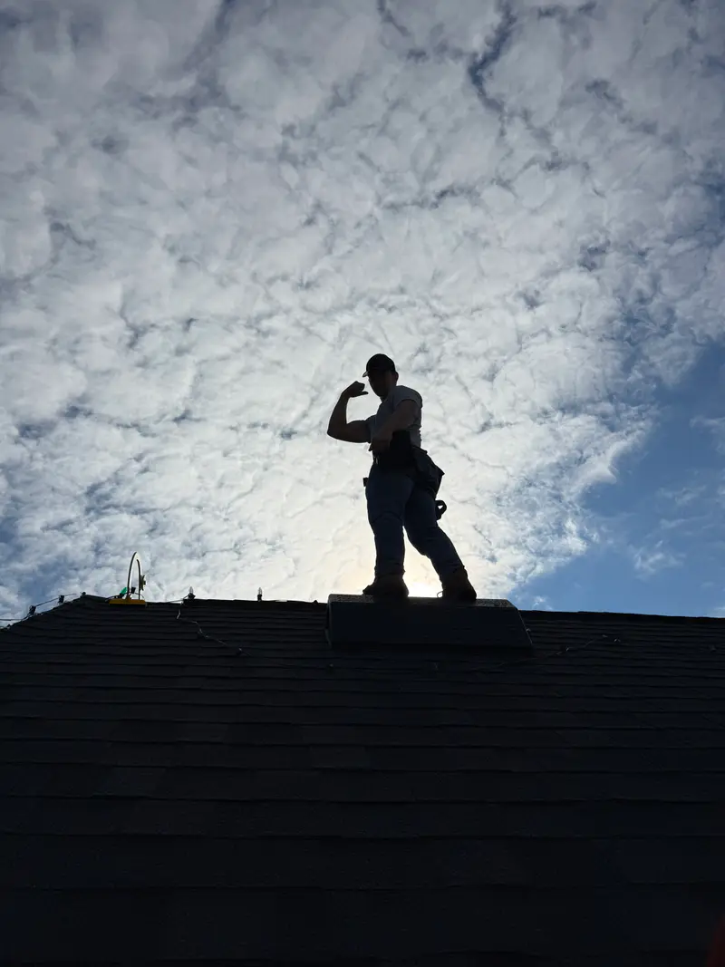 Installer silhouetted on a roof ridge against a bright winter sky